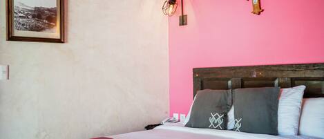 A bed with a striped blanket, a wooden headboard, and two pillows with geometric patterns.