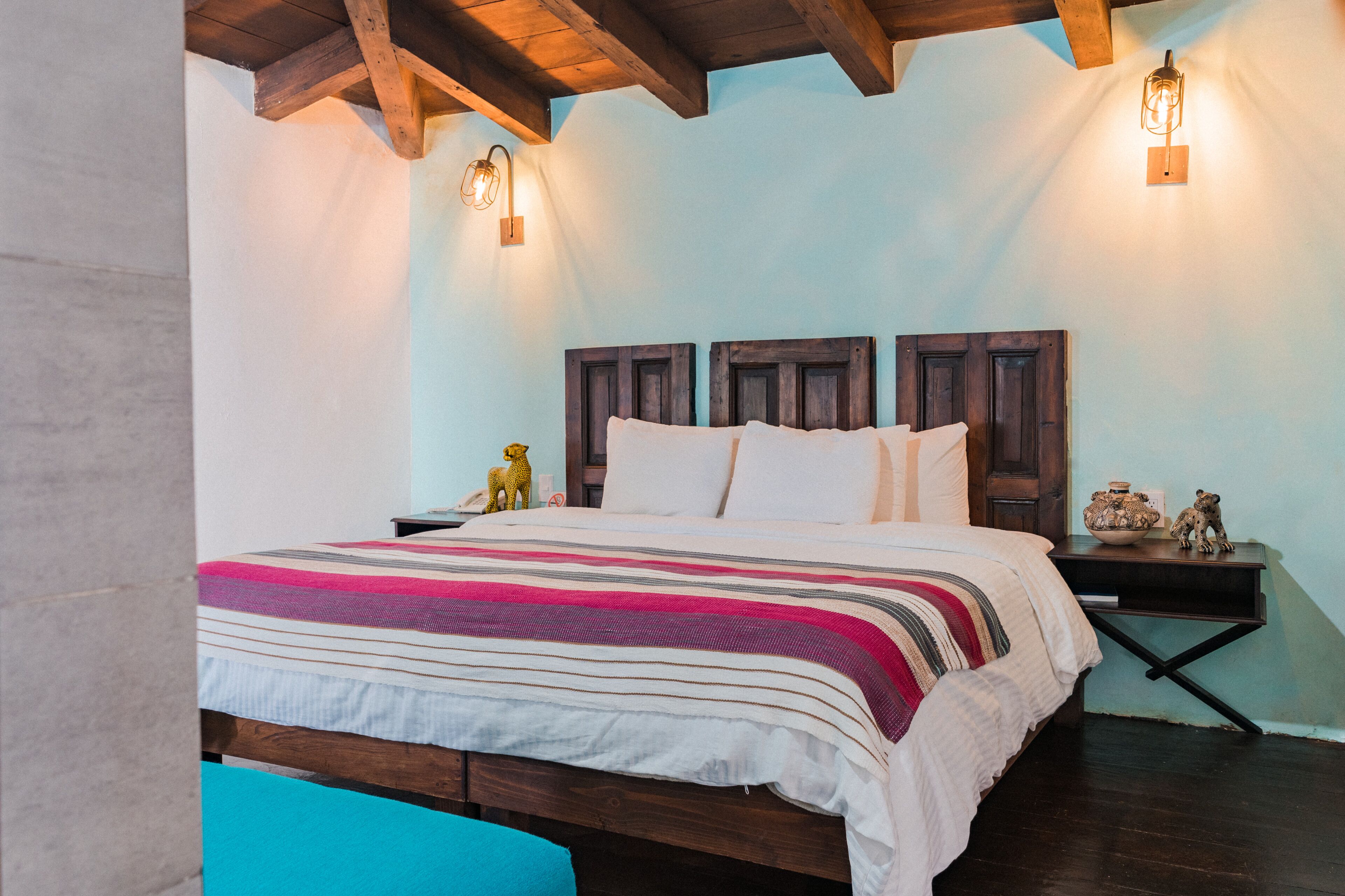 A bedroom with a wooden headboard, a striped bedspread, and two bedside lamps.
