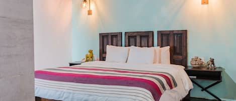 A bedroom with a wooden headboard, a striped bedspread, and two bedside lamps.