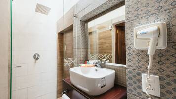 Un baño con un lavamanos blanco, un espejo y un cabezal de ducha de mano.