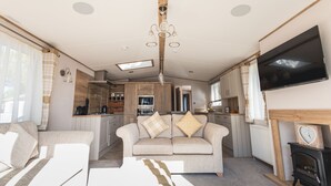 A spacious living room with a sofa, a TV mounted on the wall, and a fireplace.