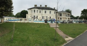 A large, cream-colored building with a pool and outdoor seating.