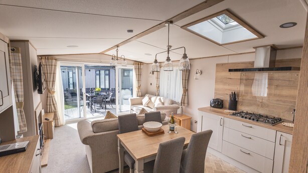A modern kitchen with a dining area, a sofa, and a view of the outdoors.