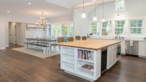 Una cocina amplia con una isla grande, armarios blancos e iluminación colgante.