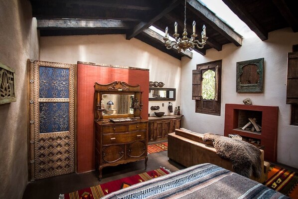Une chambre traditionnelle avec une commode en bois, un miroir, un canapé et une cheminée.
