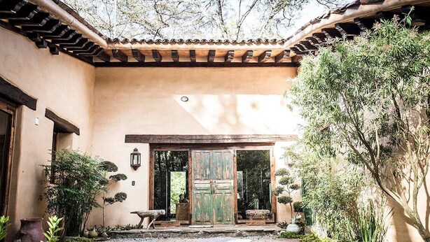 A courtyard with a traditional tiled roof, a stone bench, and a small water feature.