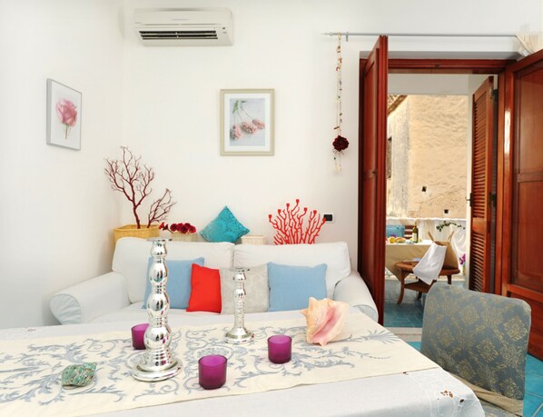 A cozy living room with a white sofa, decorative pillows, a table with candles, and a view of an outdoor terrace. - Mirtillo, Close to the Beach, Private terrace by Amalfivacation.it (MINORI)