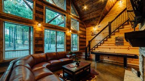 A log cabin interior with a leather sofa, a coffee table, and a staircase. - Fishin' in the Dark- private shoreline view for lounging or fishing (broken bow)