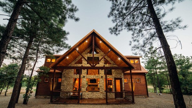 A log cabin with a stone fireplace, wooden deck, and a stone chimney. - Fishin' in the Dark- private shoreline view for lounging or fishing (broken bow)
