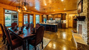 A spacious wooden interior with a dining area, kitchen, and stone fireplace. - Fishin' in the Dark- private shoreline view for lounging or fishing (broken bow)