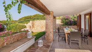 An outdoor patio with stone walls, a wooden pergola, and a dining table set for four. - Villa Belle: private pool near the beach (Aglientu)