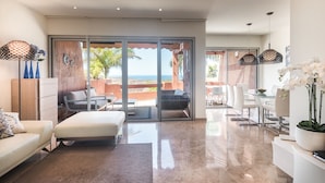 A spacious living room with a large sliding glass door leading to a balcony with a view of the ocean. There are two sofas, a coffee table, and a dining area with a glass table and chairs. - Bahia - Alzaro 1.2 DELUXE SEA VIEW & JACUZZI 3B (Arona)