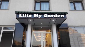 Rakennuksen sisäänkäynnin yläpuolella on kyltti, jossa lukee: ”Elite My Garden”.