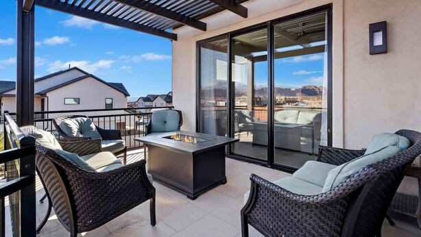 A balcony with wicker furniture, a fire pit, and a glass door leading to a patio.