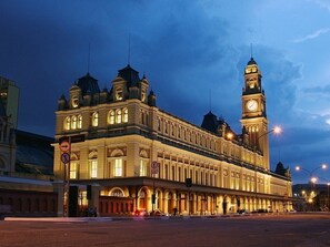 A historic building with a prominent clock tower, large arched windows, and a symmetrical facade.