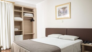 Un dormitorio ordenado con cama, mesita de noche, armario y un cuadro en la pared.