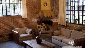A rustic room with brick walls, a fireplace, and two sofas. - Cabañas Quinta Patricia (Tequisquiapan)