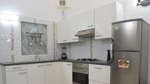 Uma cozinha moderna com armários brancos, geladeira de aço inoxidável, fogão a gás e forno embutido.