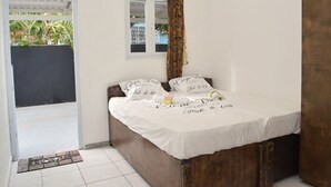 Quarto com cama, janela com cortinas e porta para o exterior.