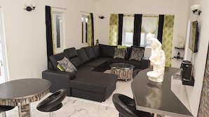 Uma sala de estar moderna com sofá seccional, uma mesa de centro redonda e um espaço bar com banquetas.