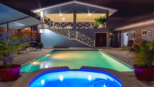 Uma casa de dois andares com uma piscina em primeiro plano.