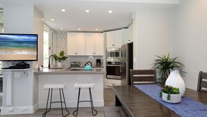 A modern kitchen with white cabinets, stainless steel appliances, and a large island with bar stools.