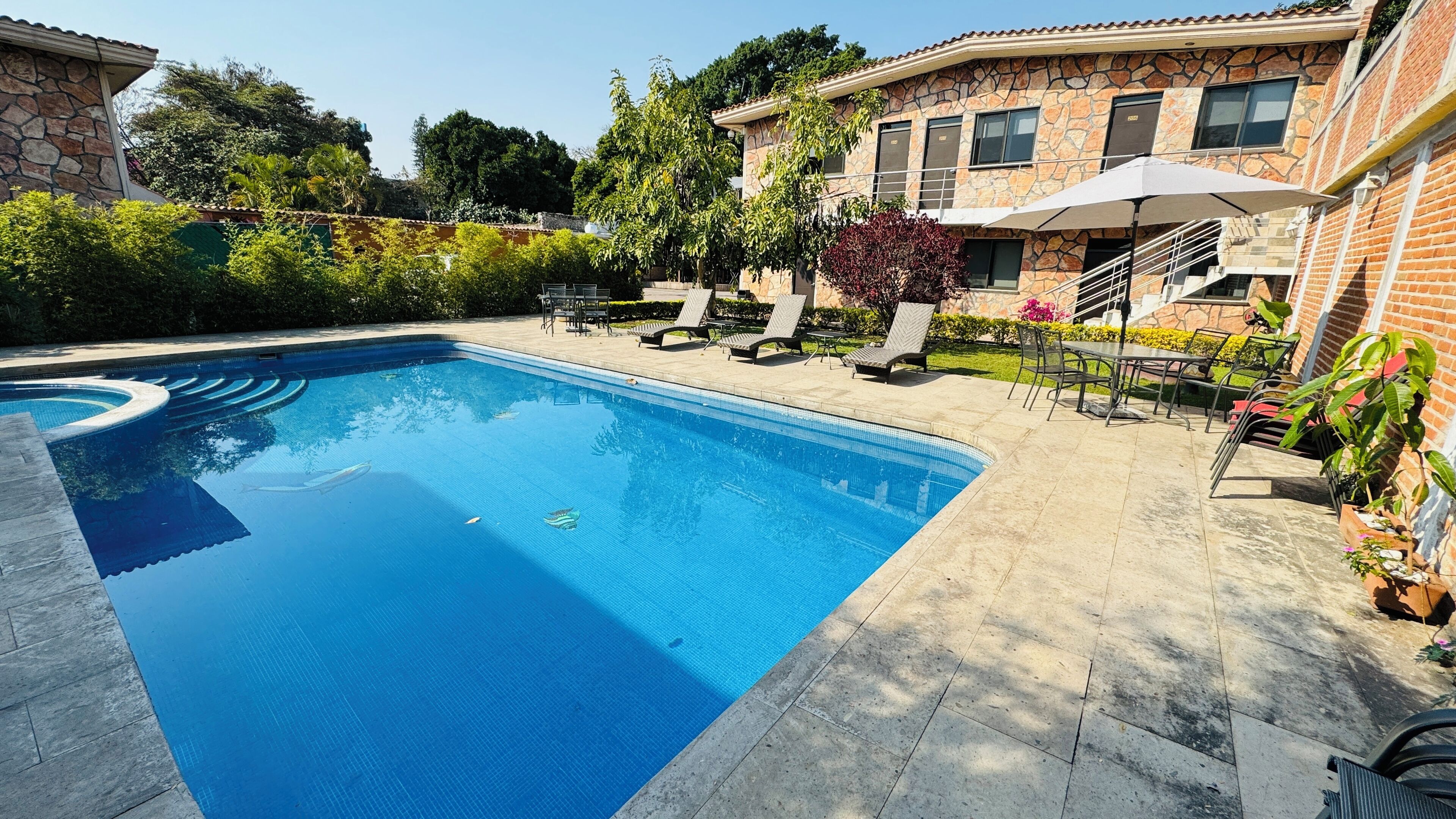 A swimming pool with a stone and brick house in the background.