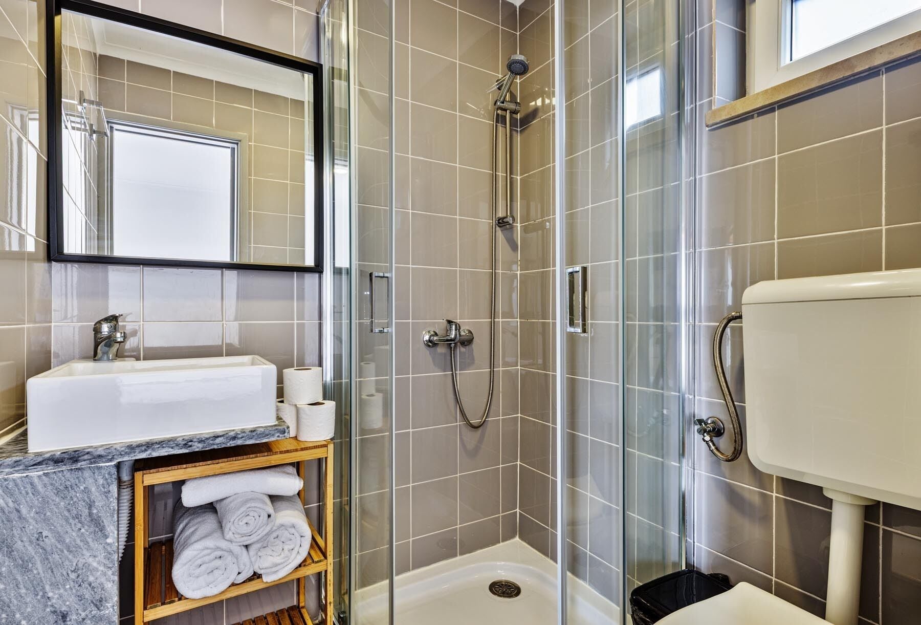 Ein modernes Badezimmer mit einer Glasdusche, einem Marmorwaschbecken und einer Toilette.