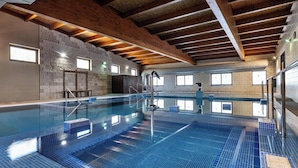 Ein Hallenbad mit gefliestem Boden und Holzbalkendecke.