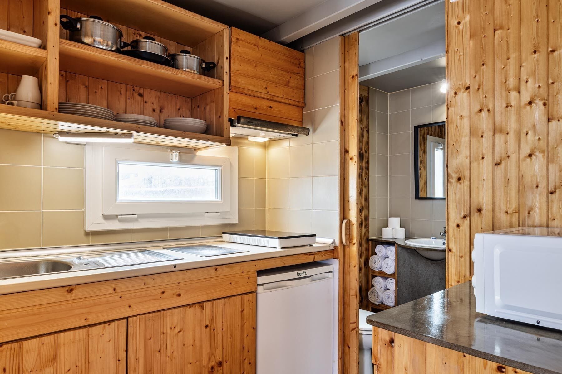 A kitchen with wooden cabinets, a built-in oven, a dishwasher, and a window above the sink.