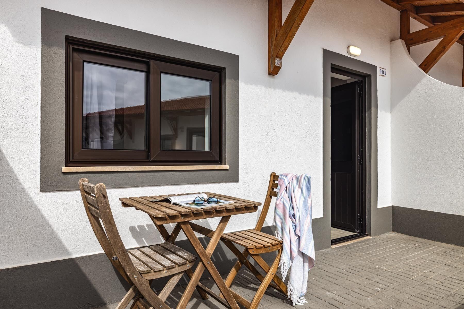 Ein Holztisch mit Stühlen vor einem Gebäude, das ein Fenster und eine Tür hat.
