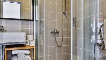 Une salle de bain moderne avec une douche à parois de verre, un lavabo doté d’un plan de travail en marbre et des toilettes.