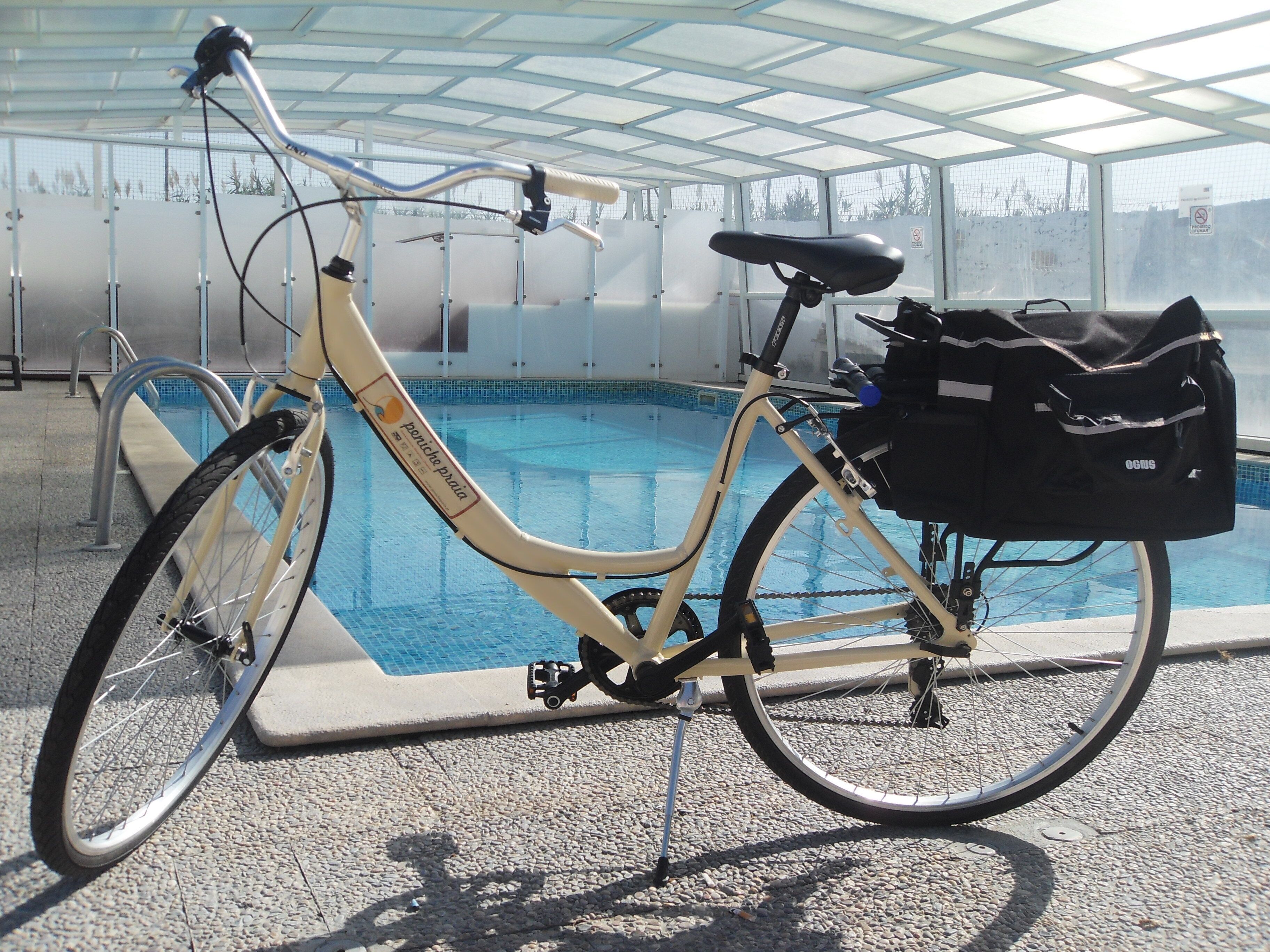 Una bicicleta estática con una bolsa de almacenamiento, ubicada al lado de una piscina.