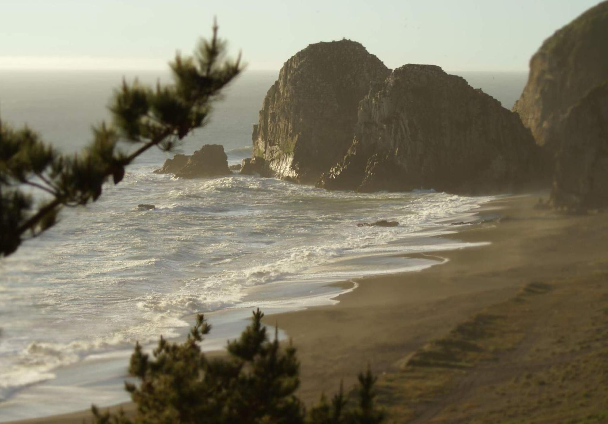 Eine Küstenlandschaft mit schroffen Klippen und einem Sandstrand.