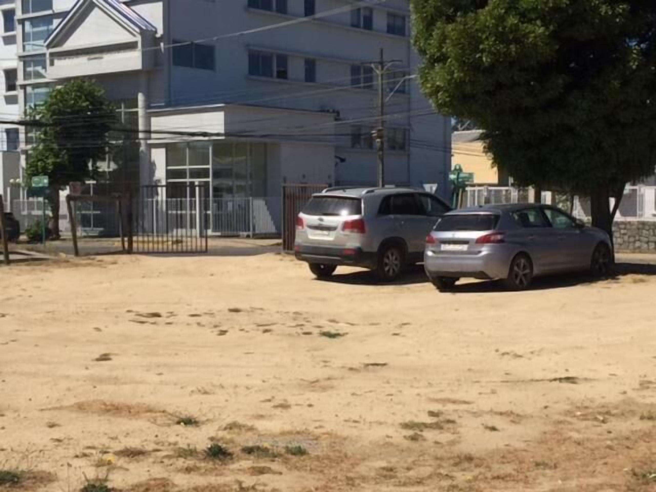 A parking area with two cars and a building in the background.