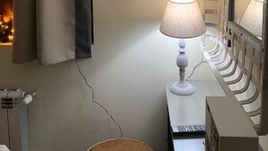A room with a bed, a bedside table with a lamp, a framed picture of a horse, and a window with curtains. - Dandy Villas Bansko | Winter Nest 1 | Prv Apartm (Bansko)