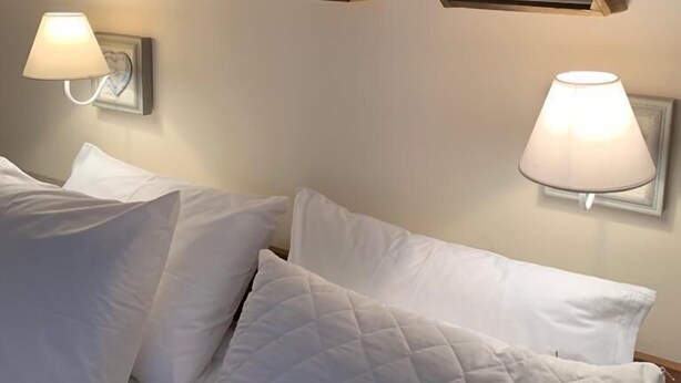 A hotel room with a bed, white pillows, and two wall-mounted lamps. - Dandy Villas Bansko | Winter Nest 1 | Prv Apartm (Bansko)