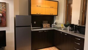 A compact kitchen with dark cabinets, a stainless steel refrigerator, a wooden countertop, and a hanging light fixture. - Dandy Villas Bansko | Winter Nest 1 | Prv Apartm (Bansko)