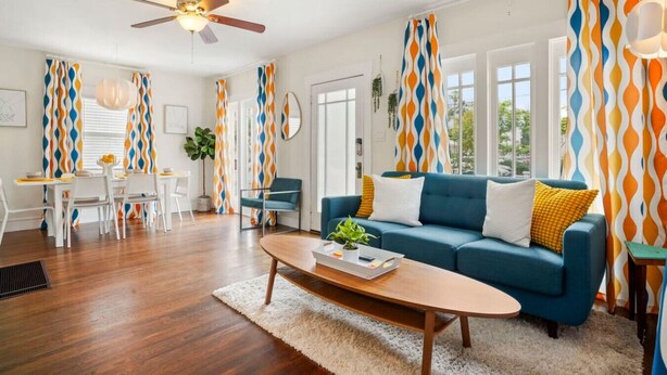 A living room with a blue sofa, white coffee table, and patterned curtains. - Bright and Quirky Hillcrest Craftsman (San Diego)