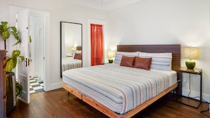 A bedroom with a bed, a ceiling fan, a nightstand, a lamp, and a mirror. - Bright and Quirky Hillcrest Craftsman (San Diego)