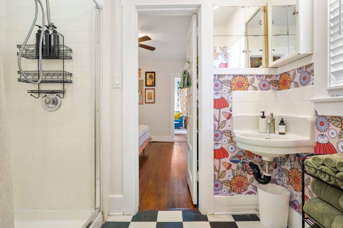 Un baño con lavamanos, ducha y toallero.