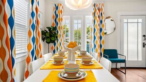 A dining room with a white table set for six, yellow placemats, and colorful striped bowls. - Bright and Quirky Hillcrest Craftsman (San Diego)