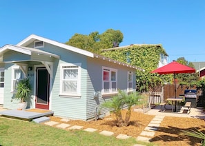 A single-story house with a front porch, a small garden, and a barbecue area.