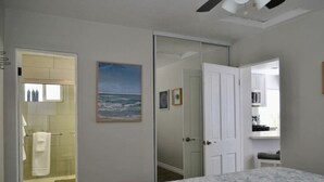 Een slaapkamer met een bed, een badkamer met een douche en een keukenhoek.