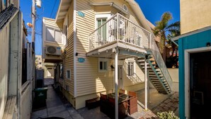 A multi-story residential building with a balcony, a staircase, and a small outdoor seating area. - Cozy & Chic 2br Retreat In Mission Beach (San Diego)