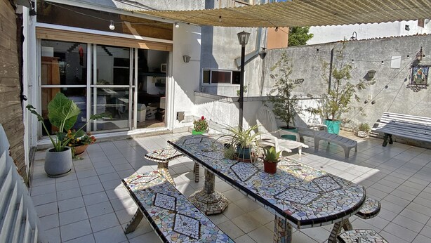 A courtyard with a tiled floor, a mosaic table, potted plants, and a bench. - Palermo Soho Hostel (Buenos Aires)