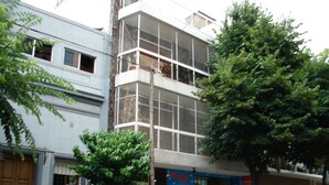 A multi-story building with a blue storefront, a white car parked in front, and a tree on the sidewalk. - Palermo Soho Hostel (Buenos Aires)