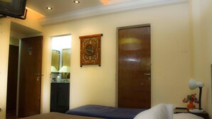 A hotel room with a bed, a desk with a lamp, a clock, and a door. - Palermo Soho Hostel (Buenos Aires)