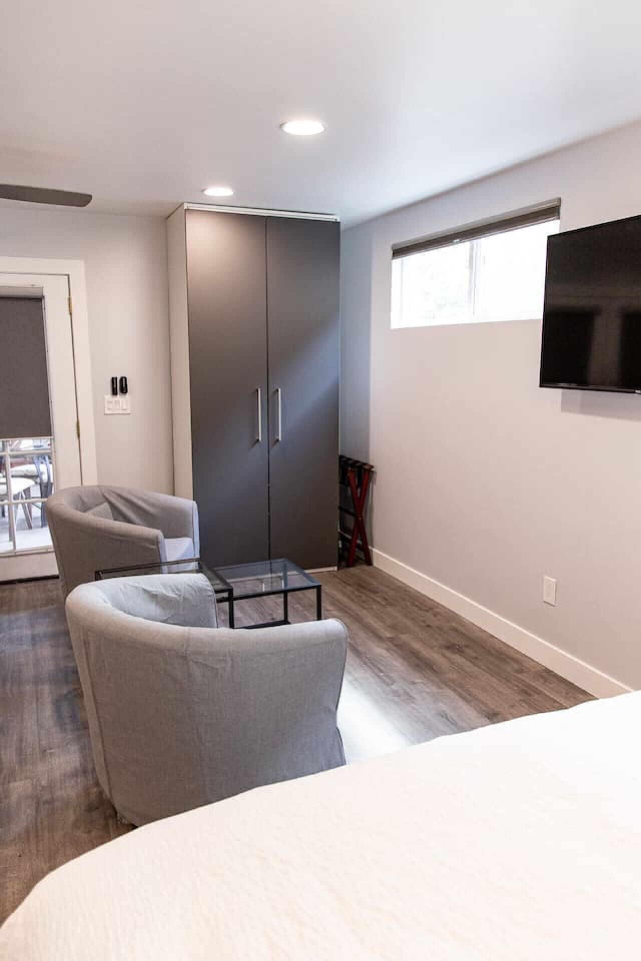 A modern bedroom with a bed, a desk, a chair, a wardrobe, and a TV.