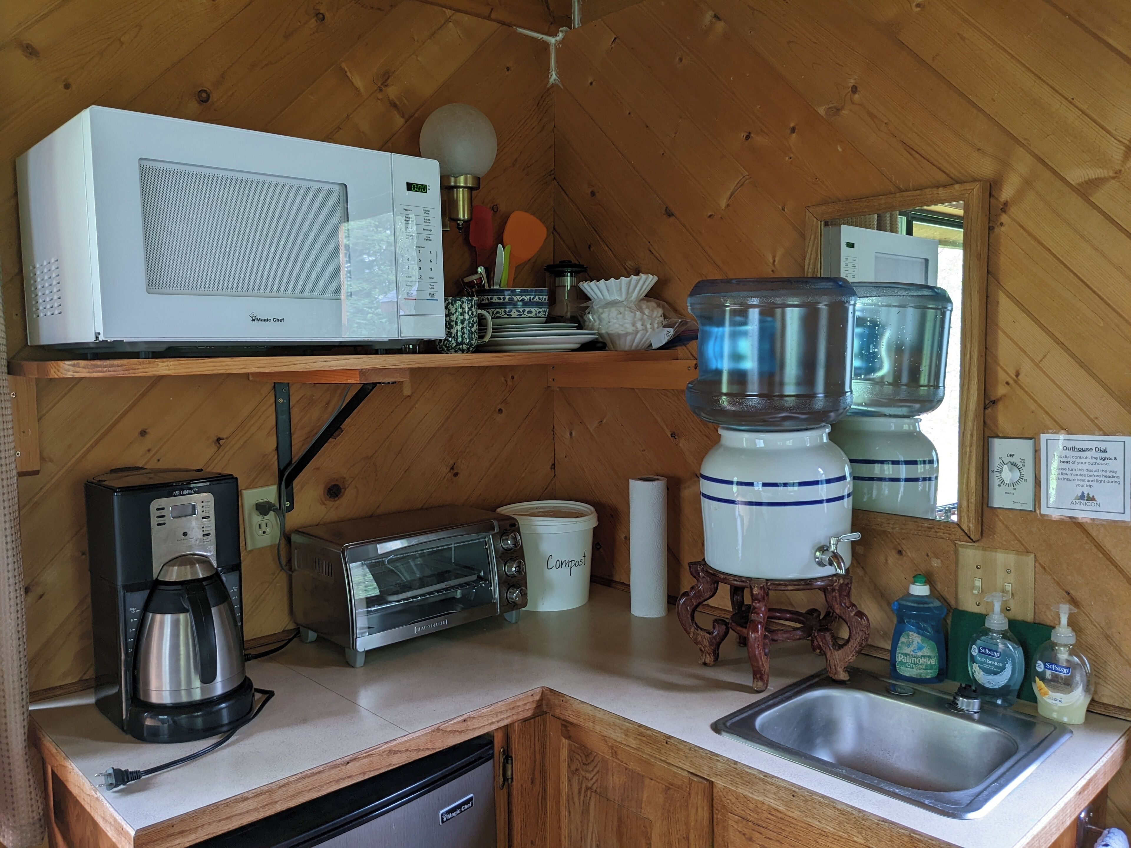 A compact kitchen with a microwave, toaster, coffee maker, and a sink.